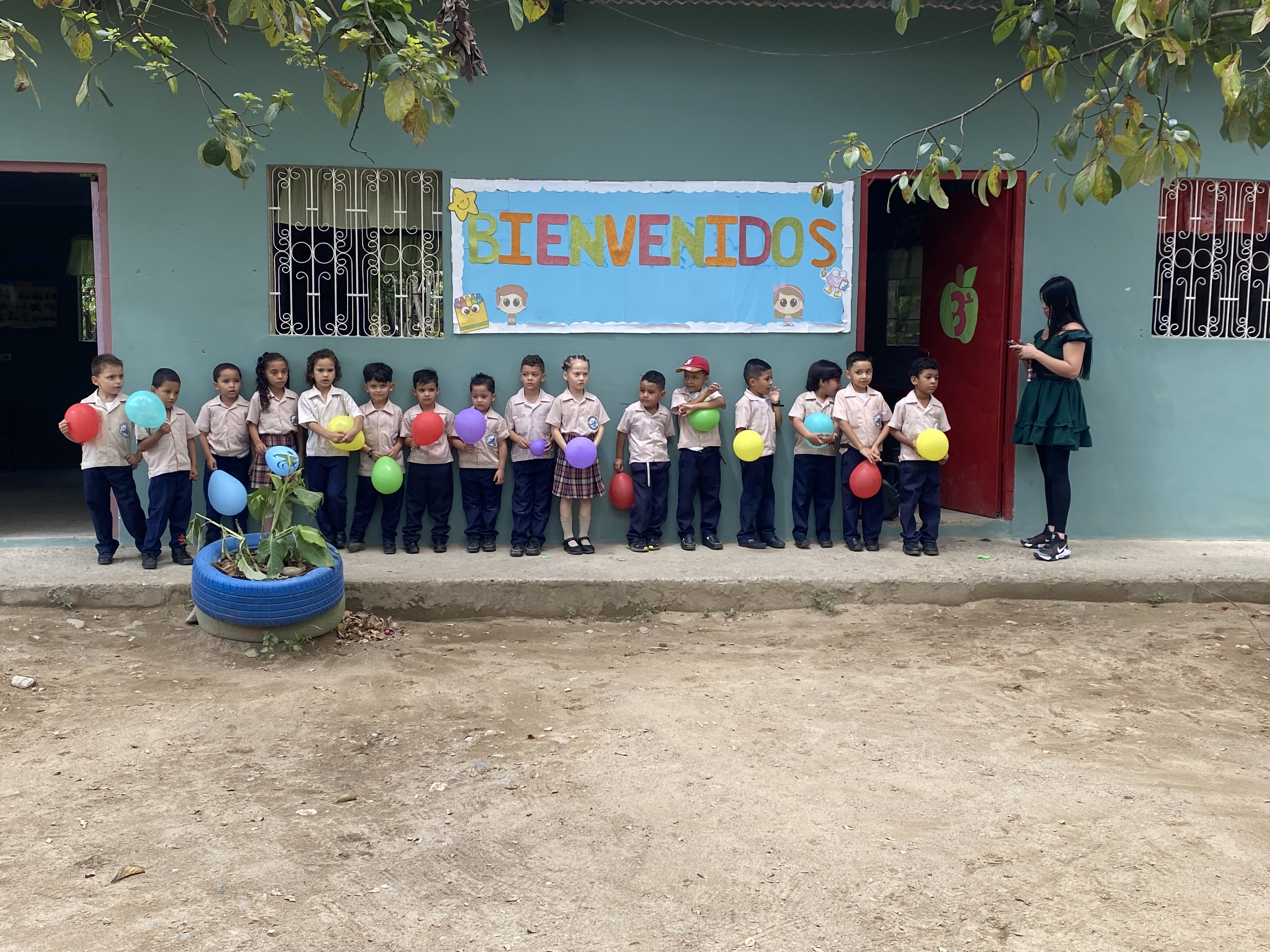 Children in uniform holding balloons at a school in Honduras.