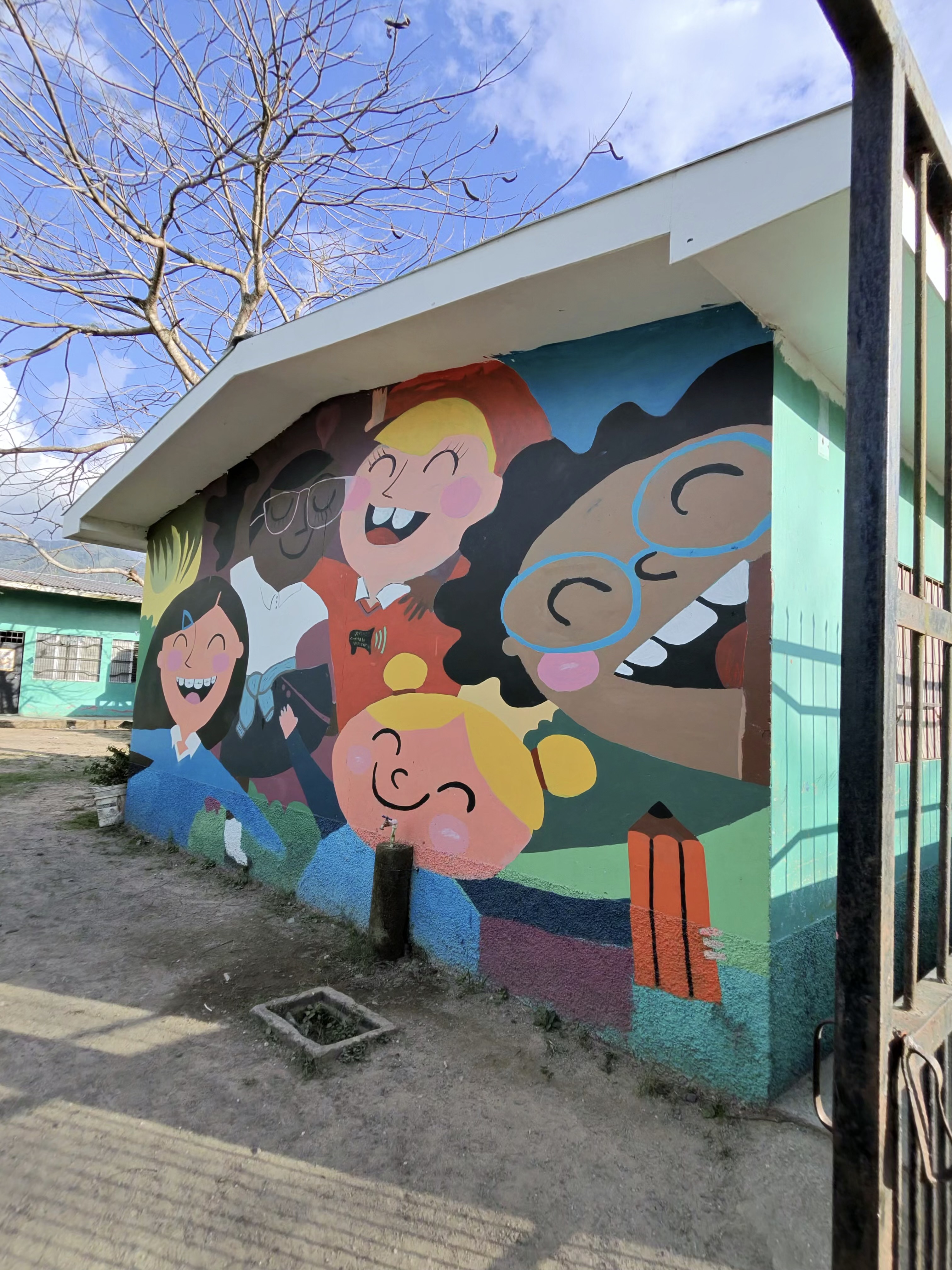 Colorful mural of smiling children painted on a Honduras schoolhouse.