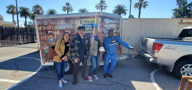 Members standing alongside the colorful Read For Life mobile library trailer.